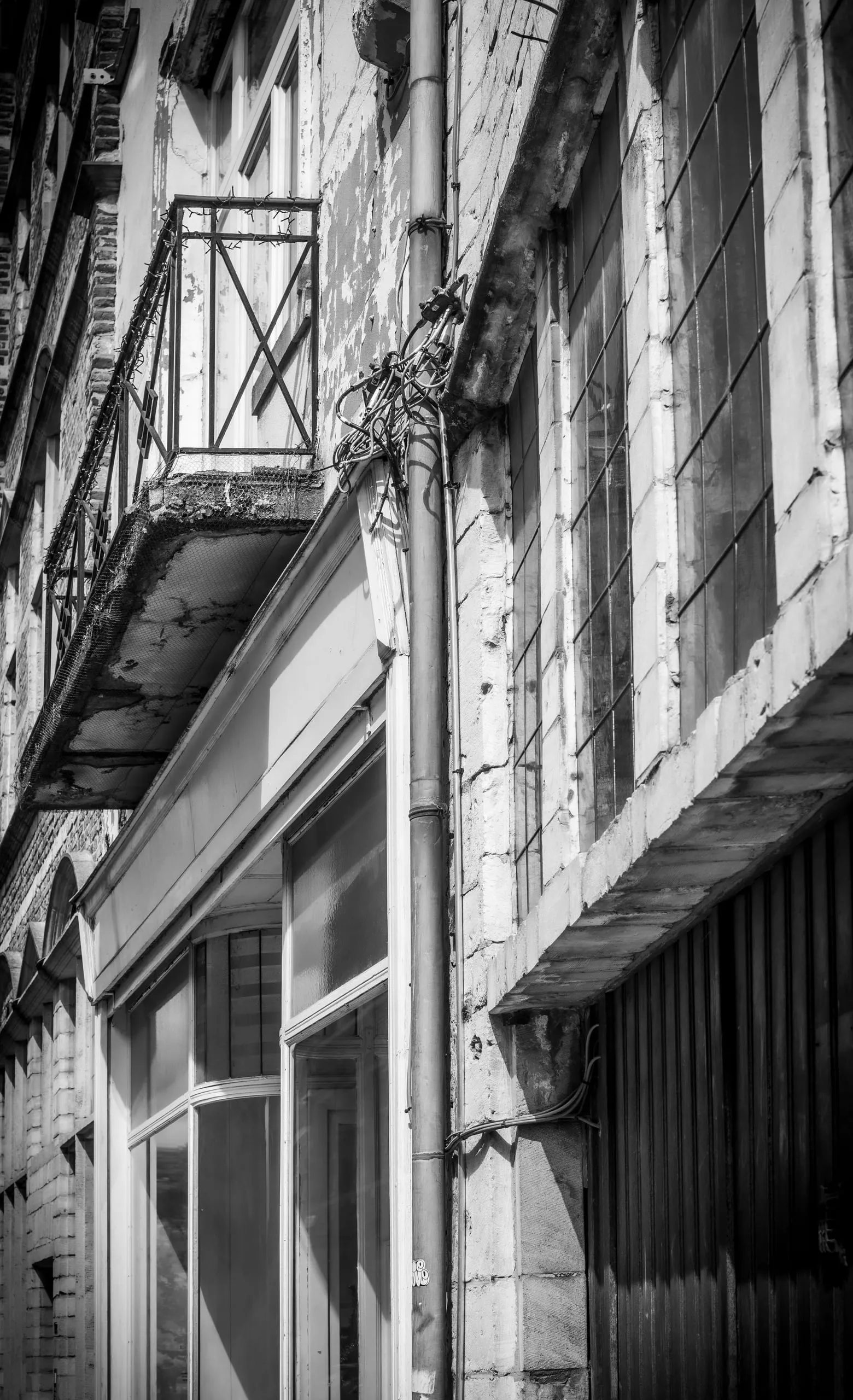 Weathered facade with a wrought-iron balcony, in black and white