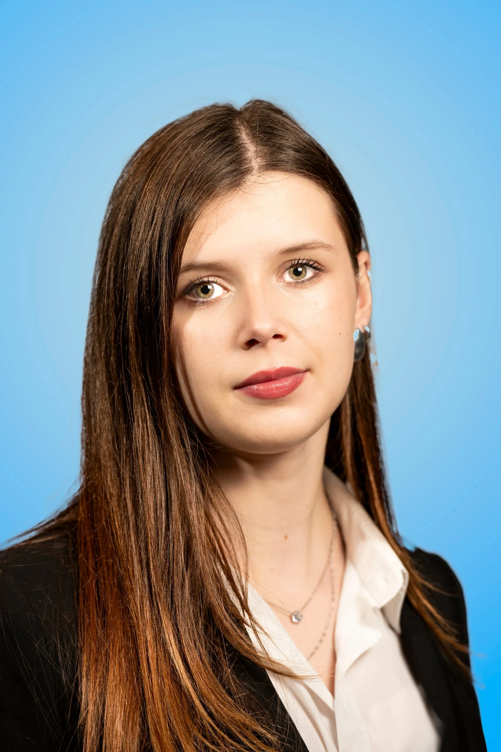 Close-up portrait of a young woman with long brown hair and a black blazer