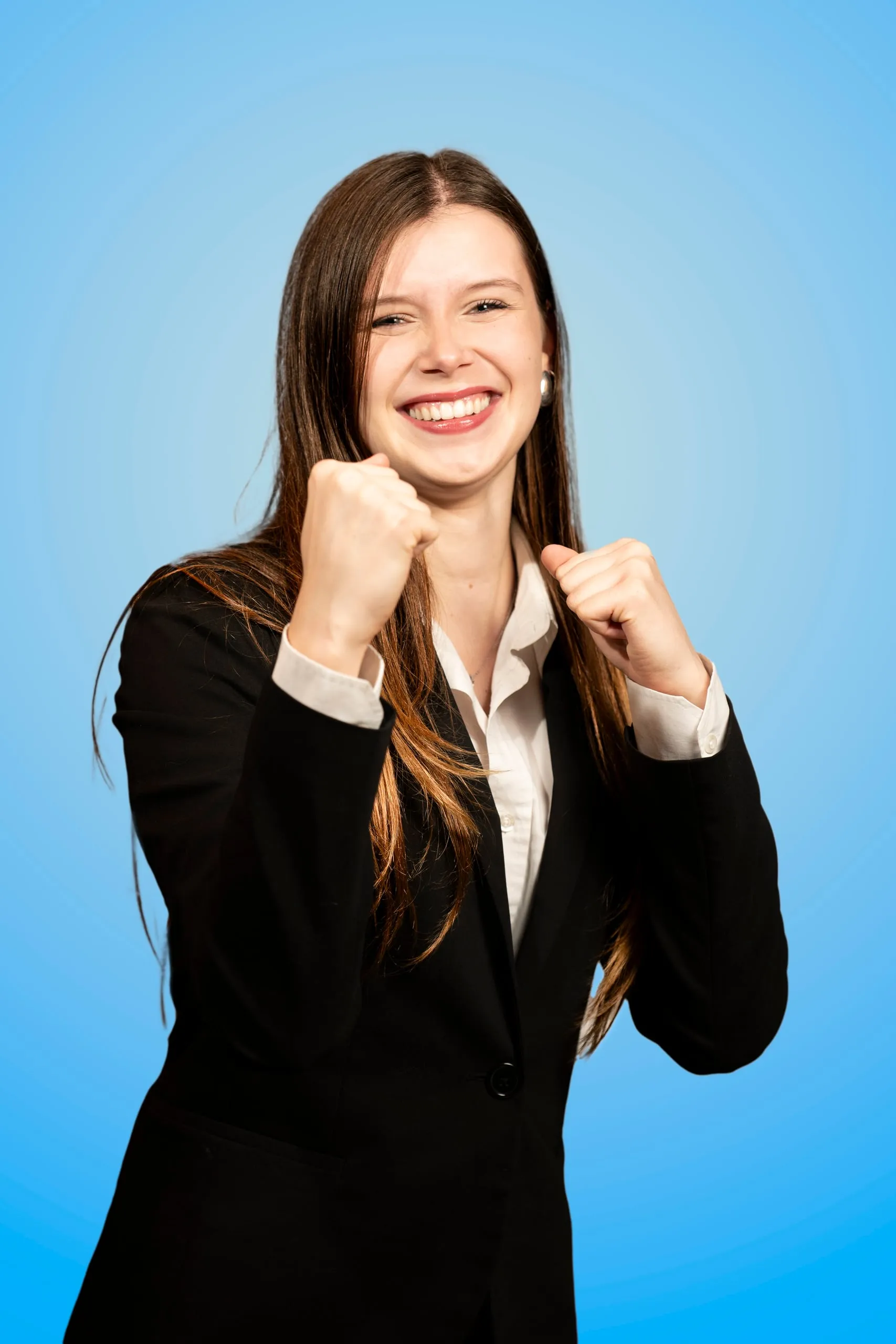 Smiling young woman in a black blazer with clenched fists