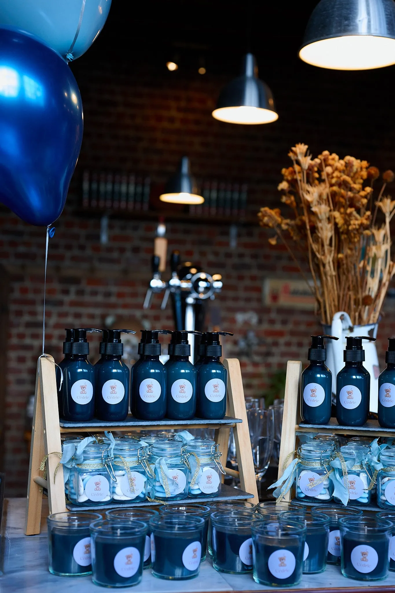 Table with dark soap bottles, glass jars and candles under blue balloons