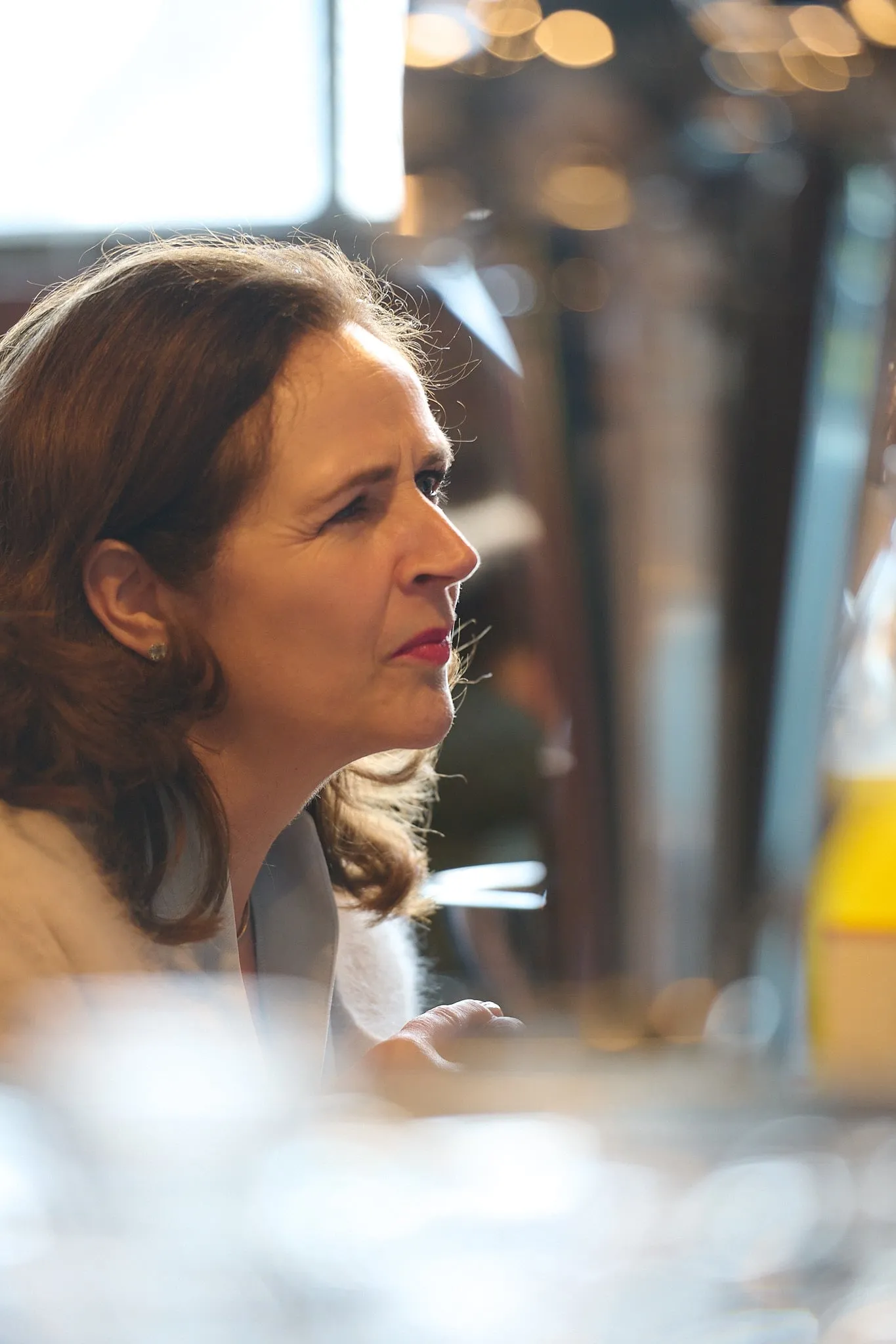 Profile portrait of a woman in conversation, with warm patches of light in the background