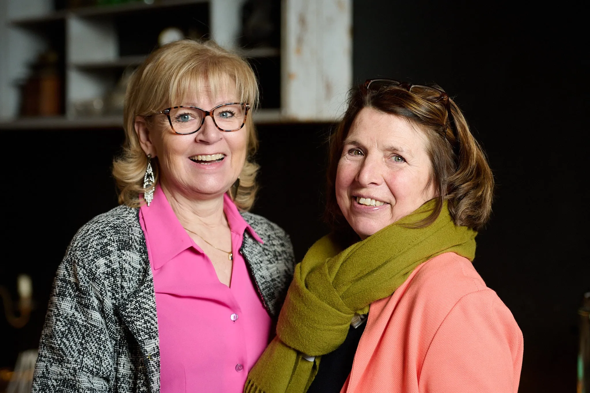 Two laughing women pose together in the café