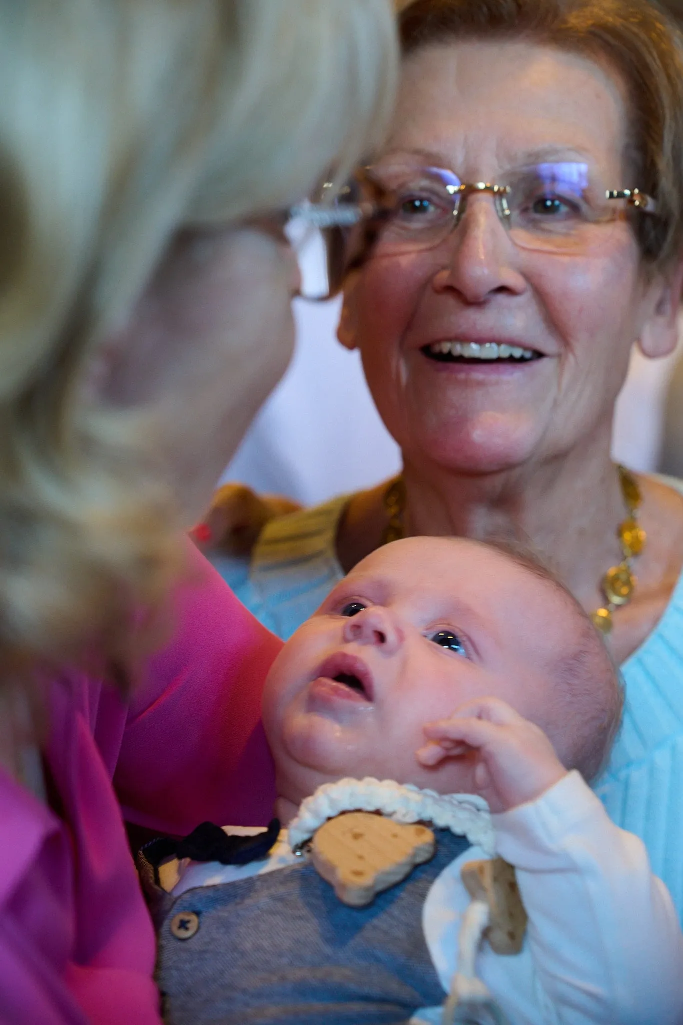Grandmother with glasses smiles at a baby in her arms