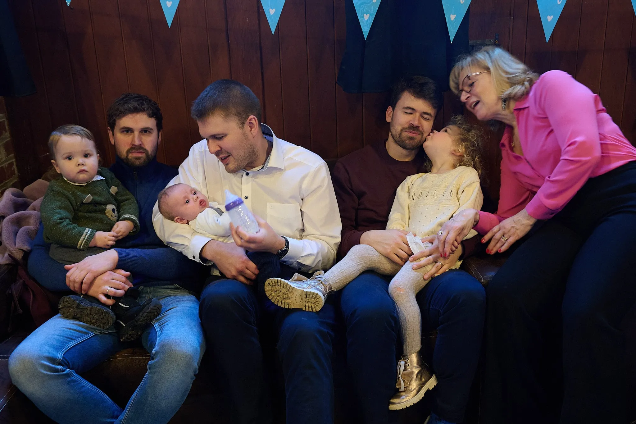 Family sitting together on the sofa with a baby, a toddler and children