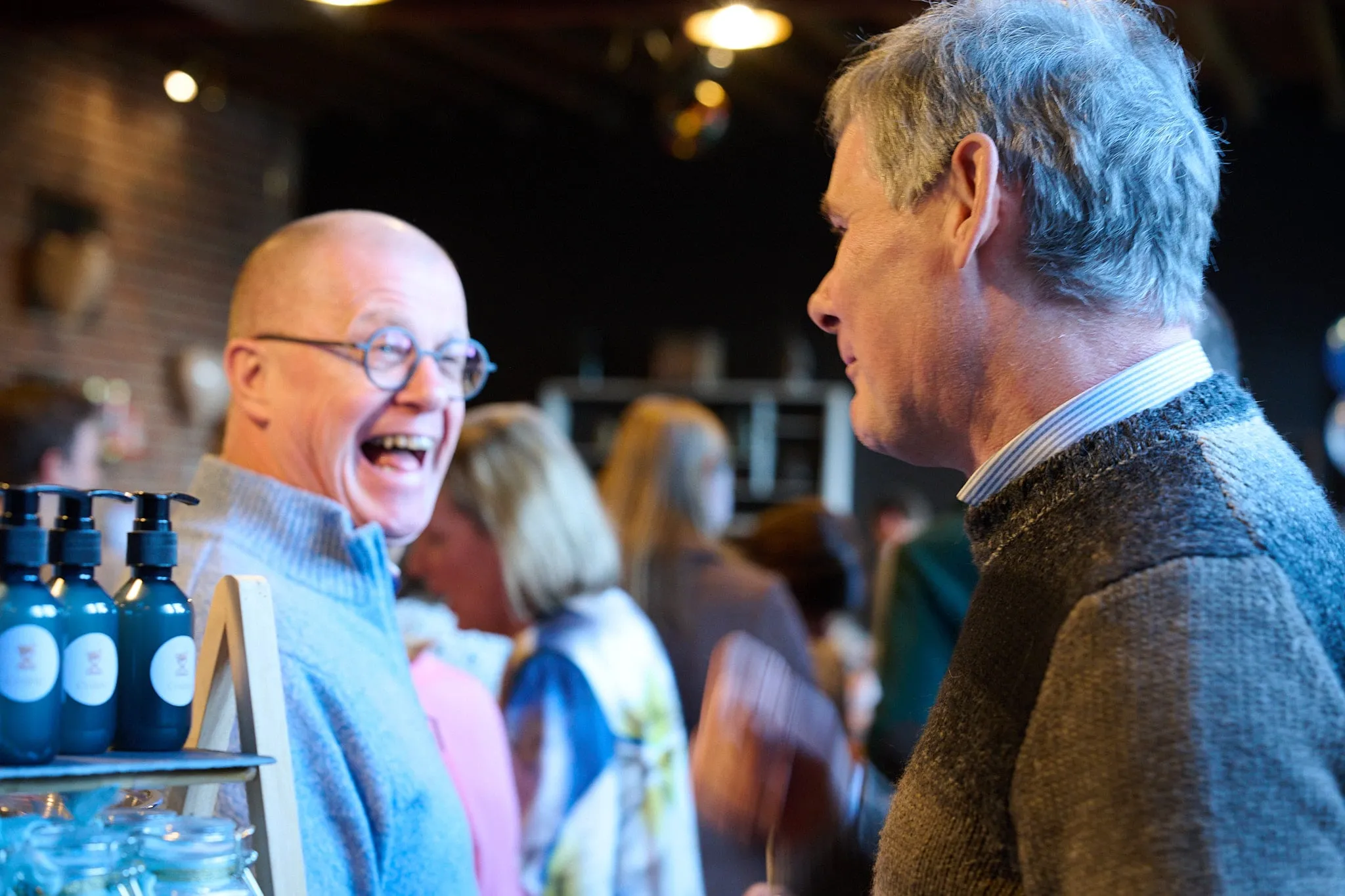 Two men in conversation, the one on the left laughing heartily