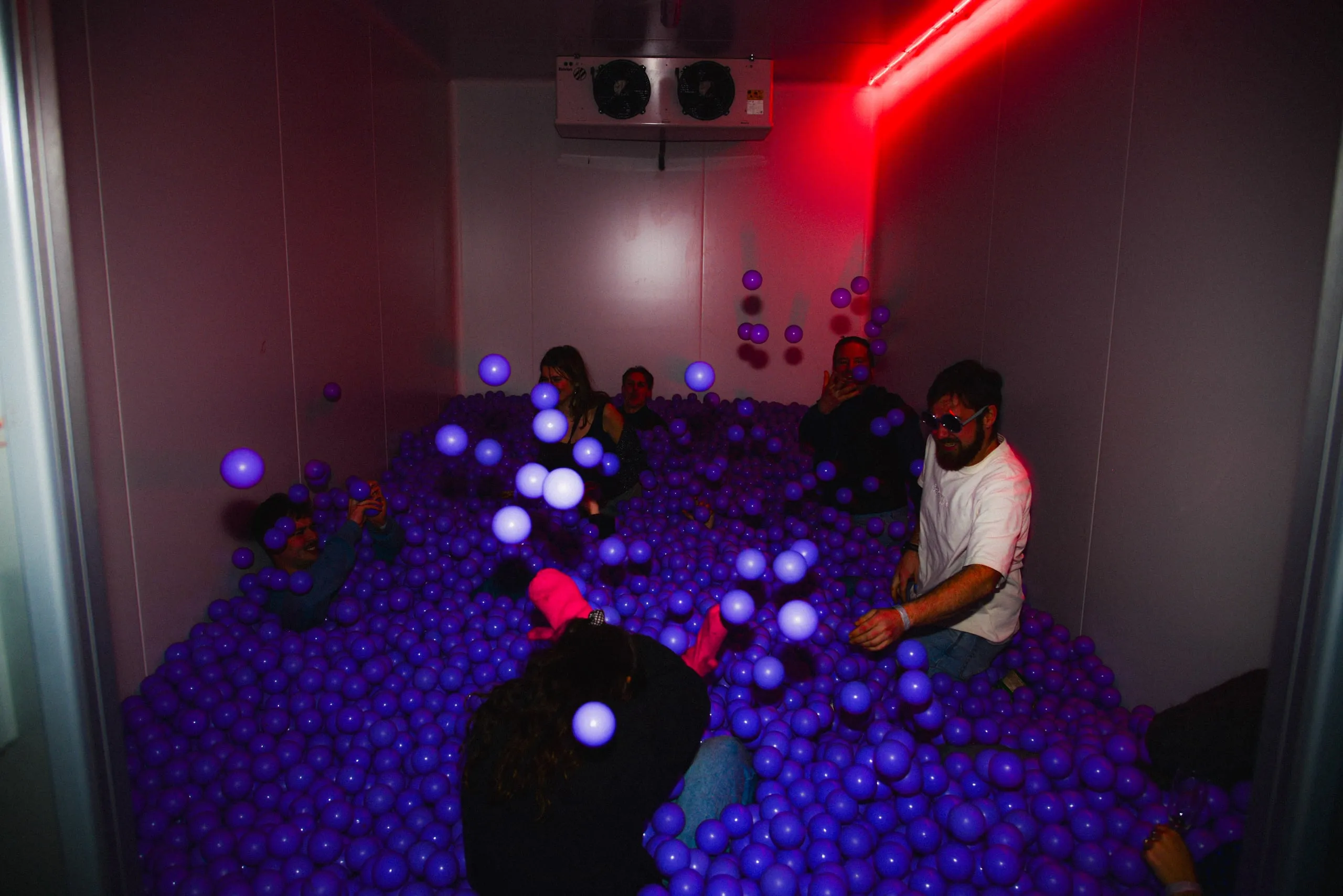 Ball pit with purple balls in a room with red neon light