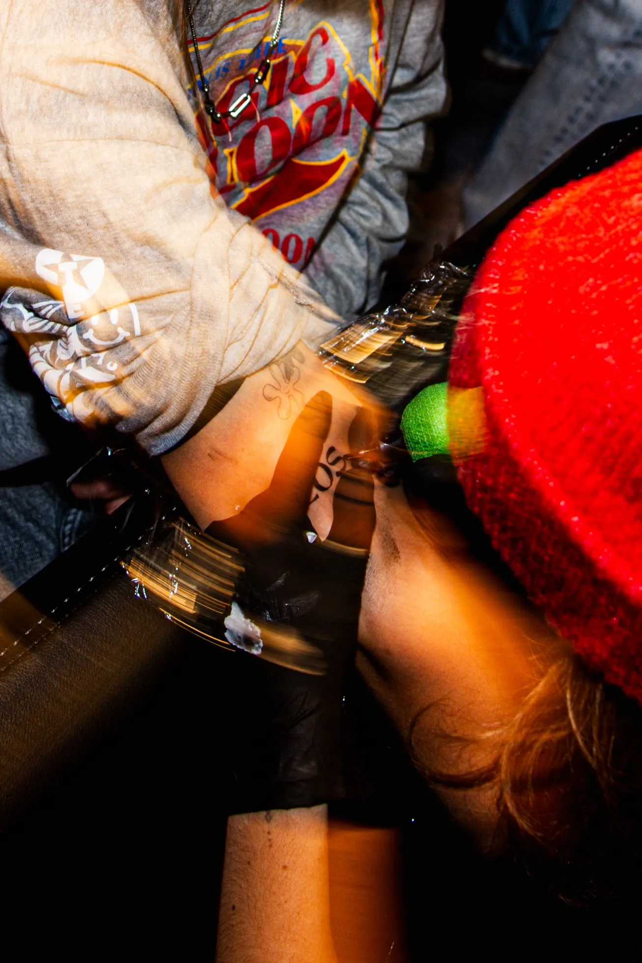 Blurred close-up of hands and a red beanie at a busy party
