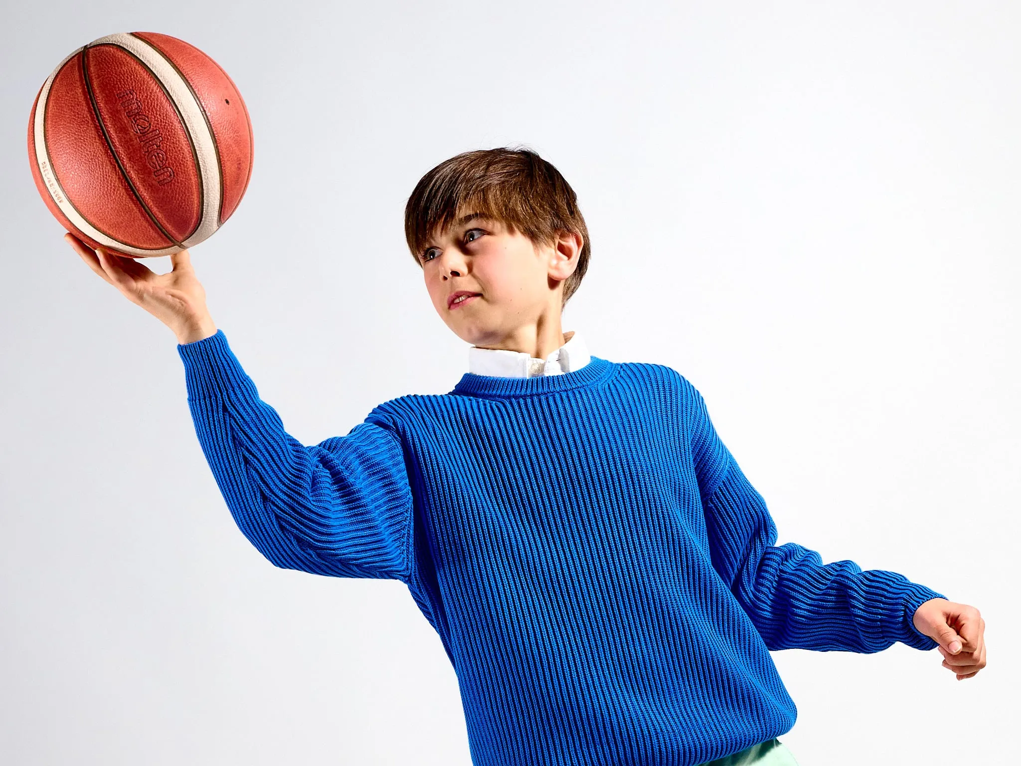 Boy in a blue sweater holding a basketball up