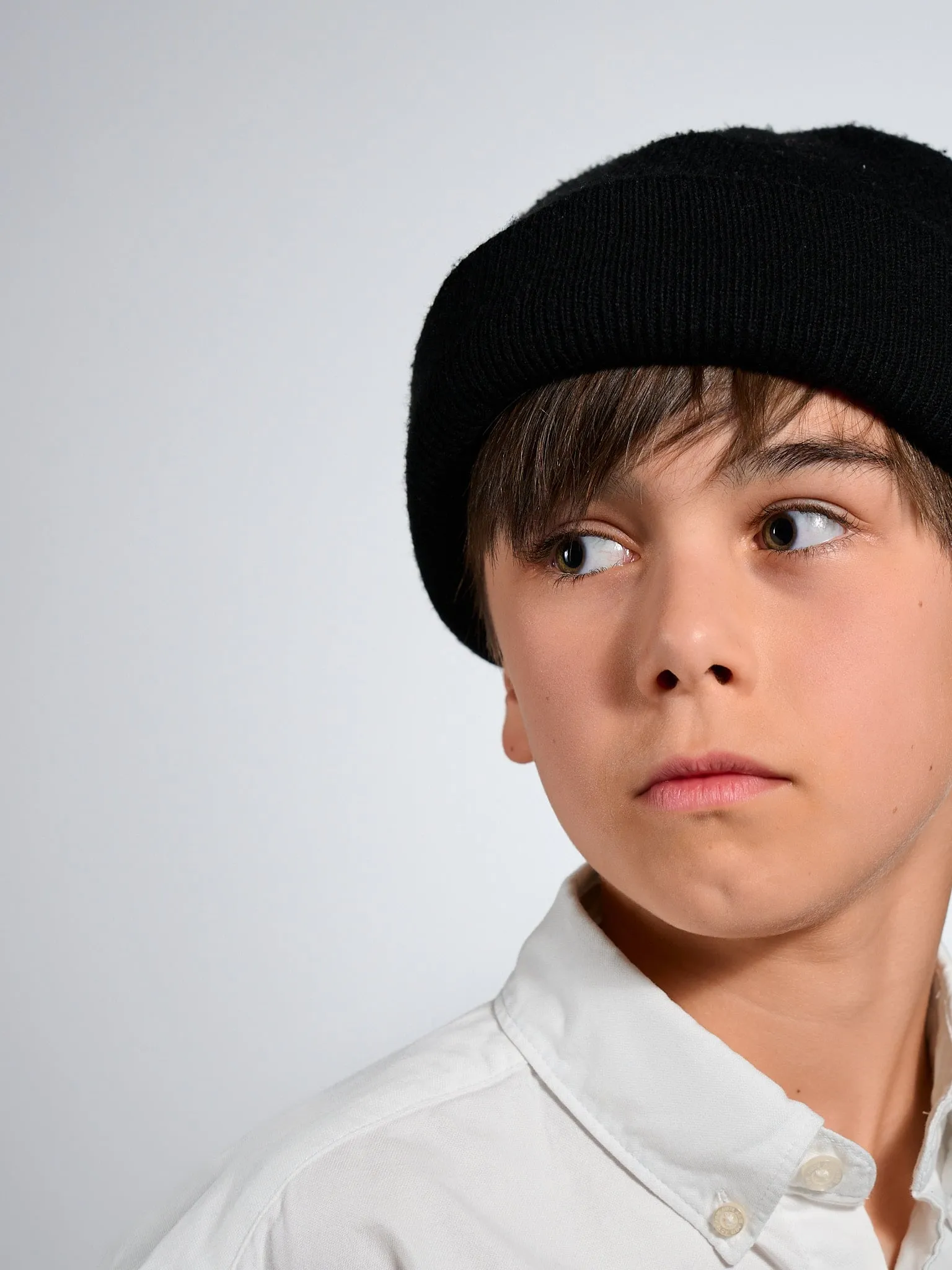 Portrait of a boy in a black beanie looking aside