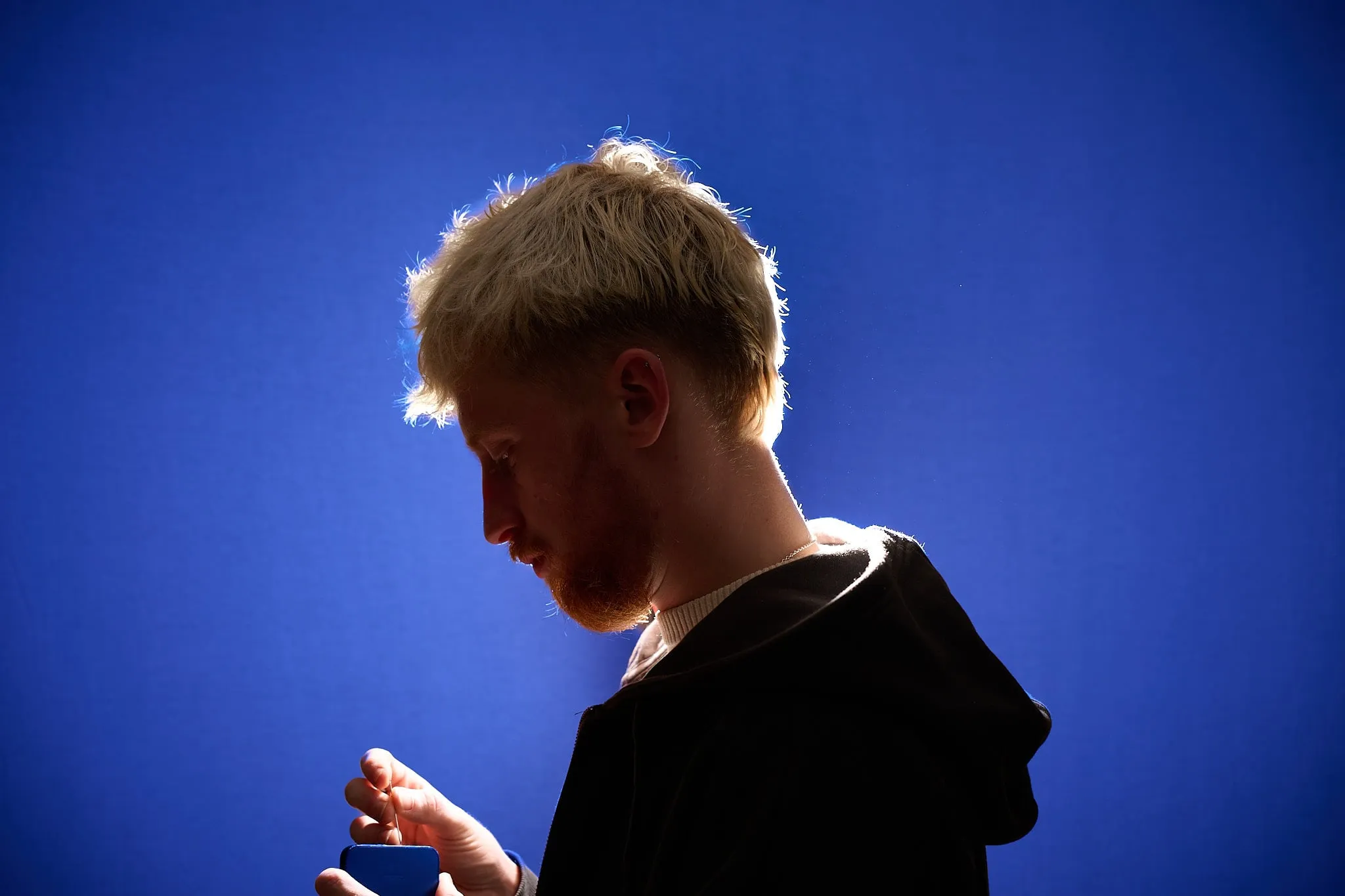 Man with blond hair in profile against a bright blue background