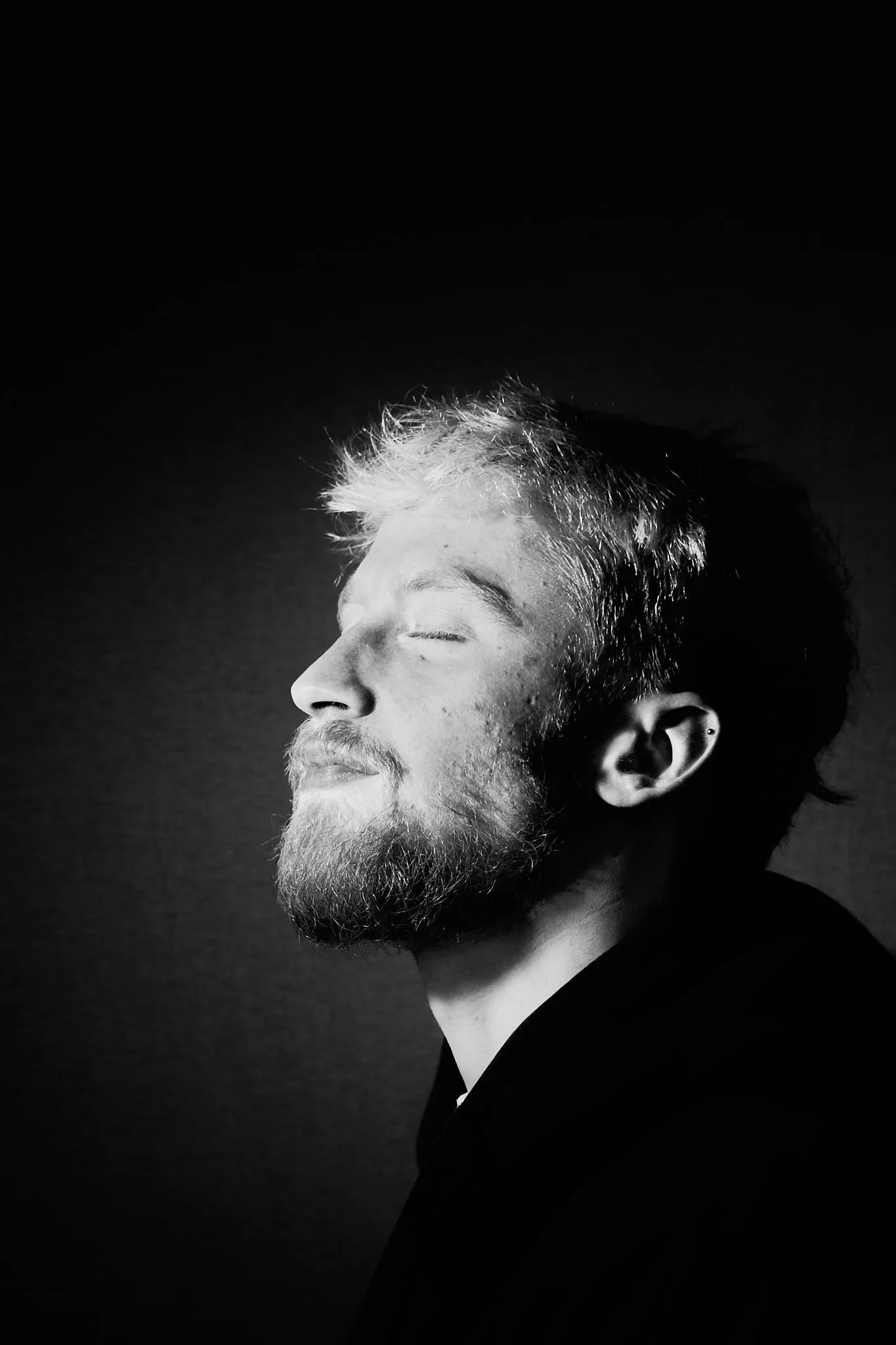 Bearded man with closed eyes, head tilted back, in black and white