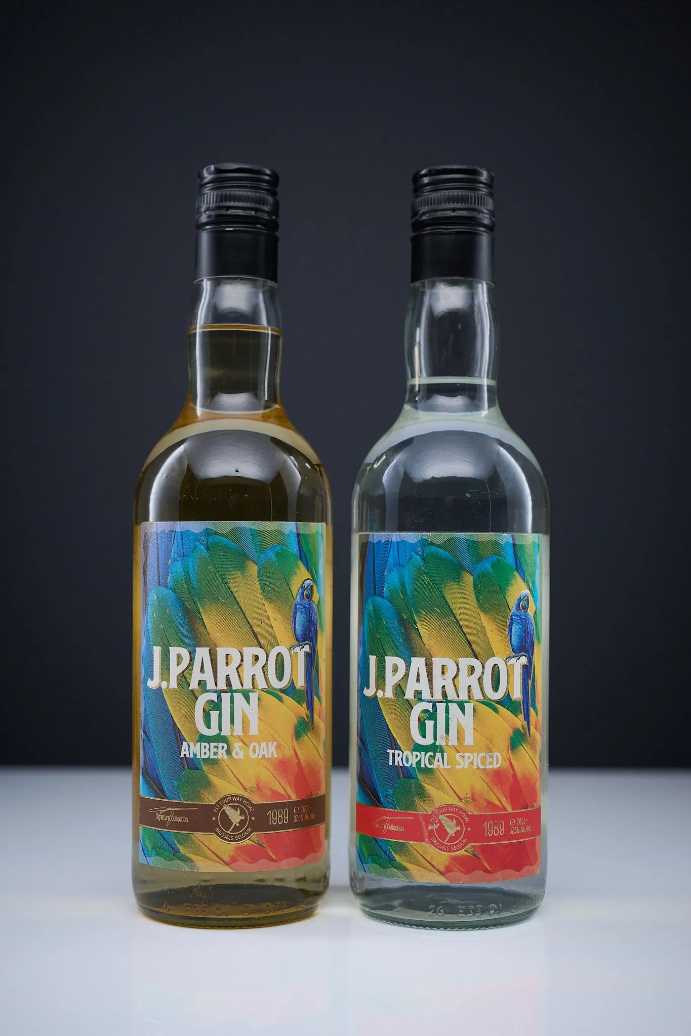 Two bottles of J. Parrot Gin, Amber & Oak and Tropical Spiced, against a dark background
